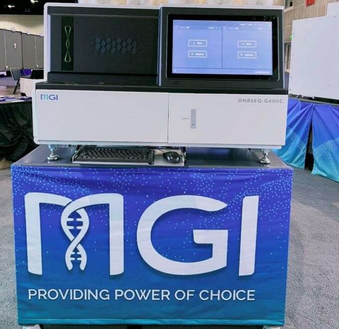 The DNBSEQ-400 sequencer on display on a table with a banner reading "MGI, Providing power of choice."