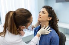 Endocrinologist examining throat of young woman in clinic