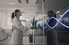 A scientist uses a large machine decorated with a DNA motif.